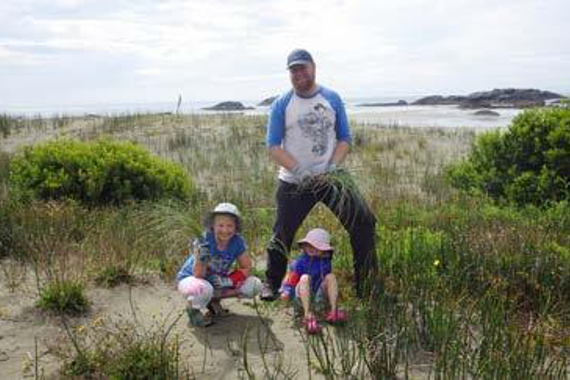A man and two children in a beach dune landscape.