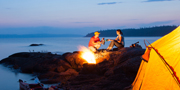 Two people sitting beside a campfire.