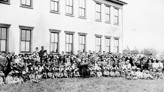 A large group of people posing for a photo in front of a building.