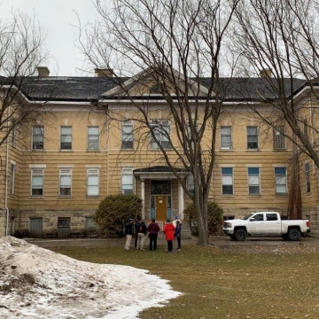 A large building with trees and people looking at the building