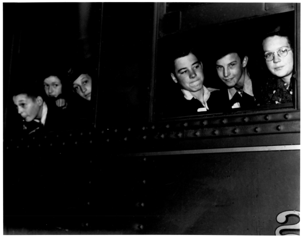 Historical photos of people's faces looking out of a train's windows