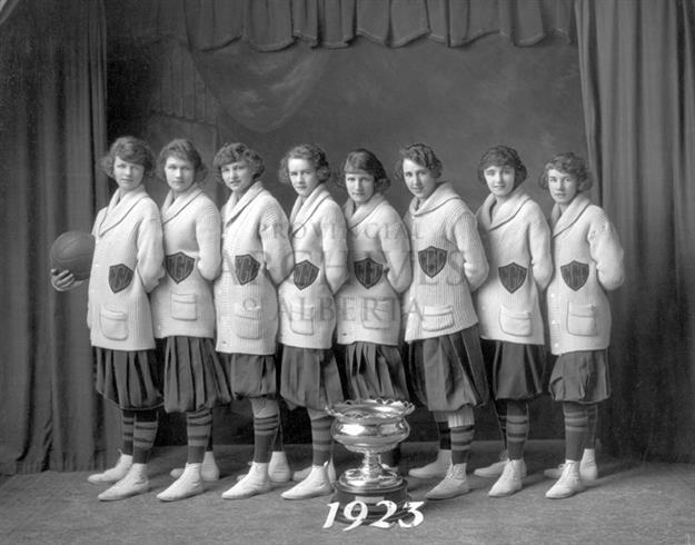 Black and white photo of a group of women, a winning cup and a basketball