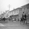 Black and white photo of people in a street and a man on a horse