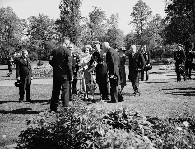 A black and white photo of people visiting a historic garden 