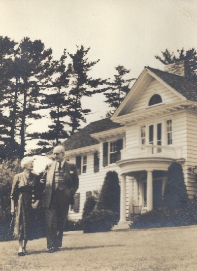 Historical photo of a women and a man standing in front of a white house