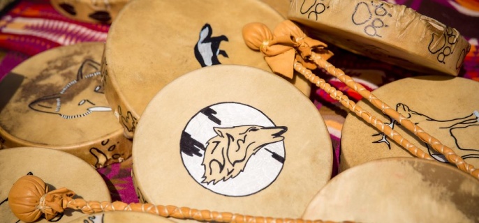 Indigenous drums and drumsticks lay scattered across a blanket