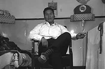 Black and white photo of a man seated on a chair