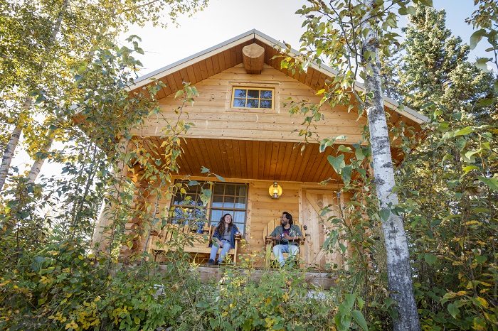 People sat on the porch of a log cabin