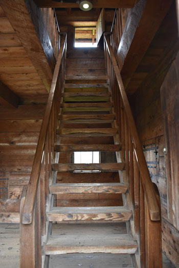 The palisade staircase is made from dark wood and has a rustic appearance. 