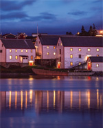 A group of white, wooden buildings next to the water