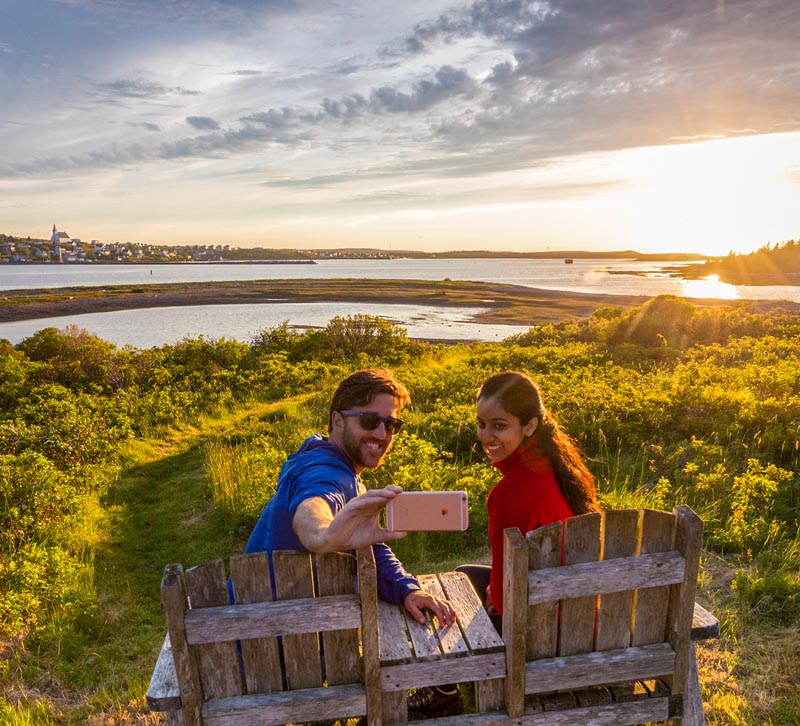 Visitors take a selfie as they enjoy a sunset view of the town of Canso from Grassy Island.