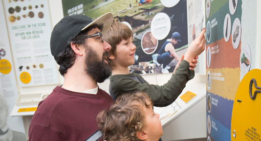  A young family explores an exhibit on the wall together.