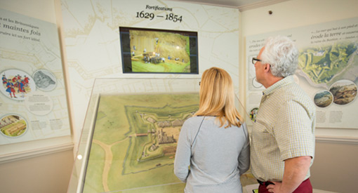  A pair of visitors looking at an exhibit about the forts.