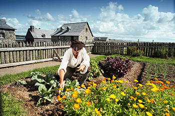 Parks Canada staff in 18th century costume tends a vegetable garden.