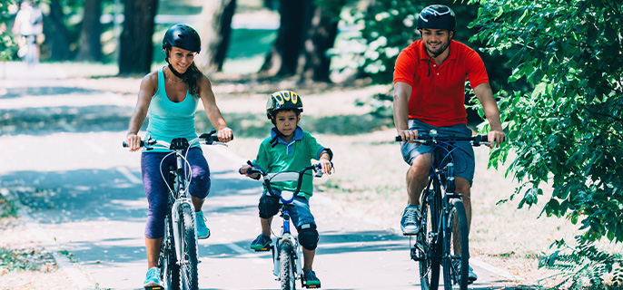A mom, dad and their child cycle along a bike path on a beautiful summer's day.