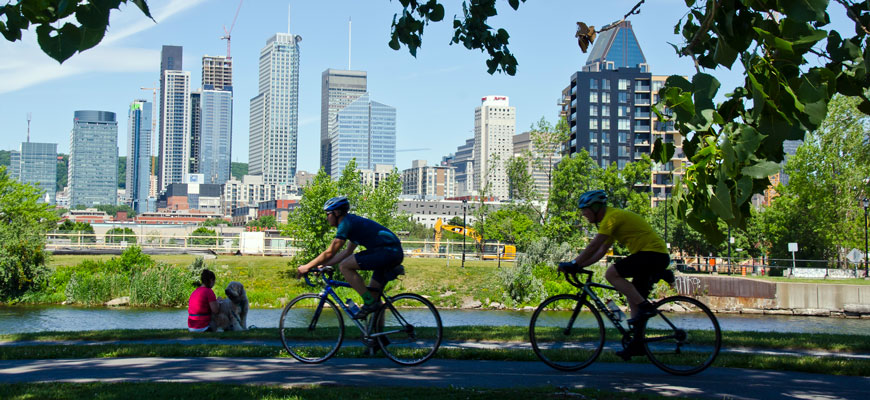 Visitors biking along the Lachine Canal with the Montreal Skyline in the background.
