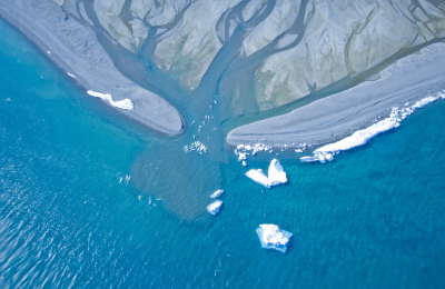 An aerial view of whales swimming at the mouth of an arctic estuary.