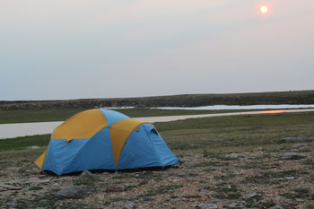 A tent on the tundra with a river in the background.