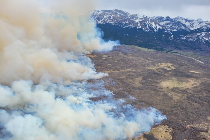 An aerial view of a prescribed fire shows smoke blowing off to the right.