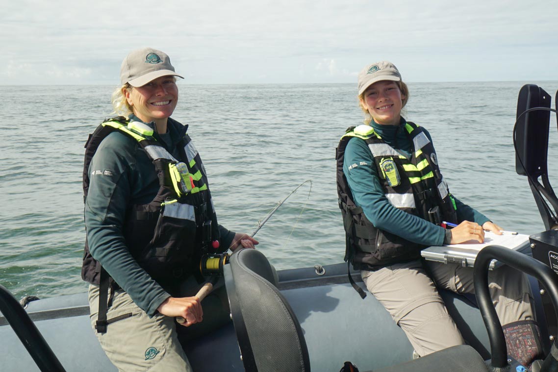 Two Parks Canada staff members onboard a boat record data during a marine mammal survey.