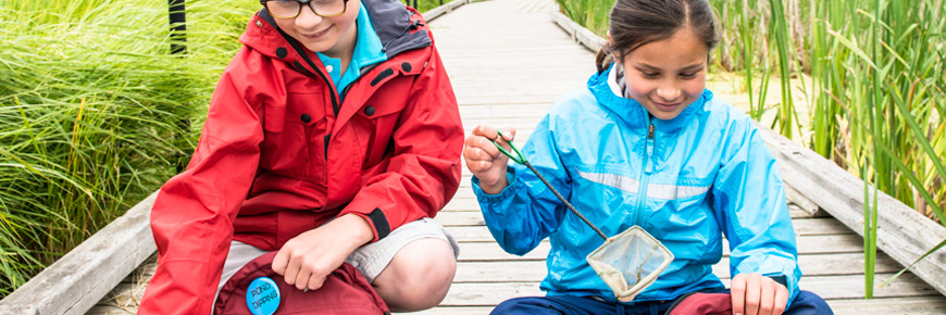 Two children look through a pair of backpacks and remove a small fishing net. 