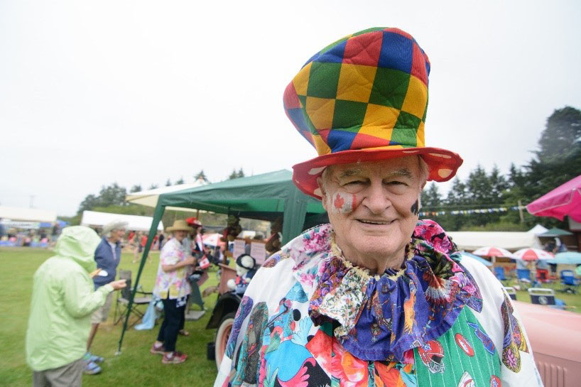 A person disguised with a hat and colorful clothes looks at the lens.