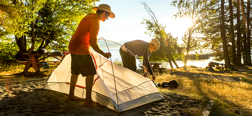 Two campers set-up their tent under the evening sun at Shingle Bay campground on Pender Island
