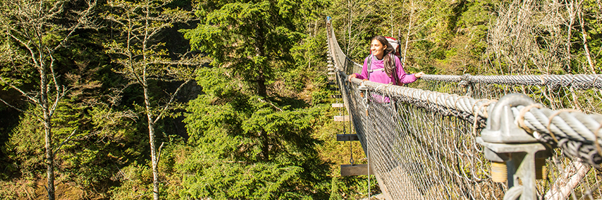 A young woman crossing a suspension bridge.
