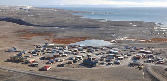 A view from the top of a hill; overlooks a small Arctic village, at the edge of the ocean.