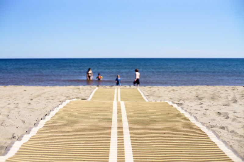 A  nonslip roll-up beach access mat on the sandy beach.
