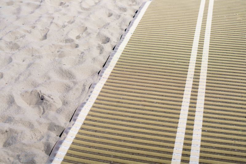 A  nonslip roll-up beach access mat on the sandy beach.