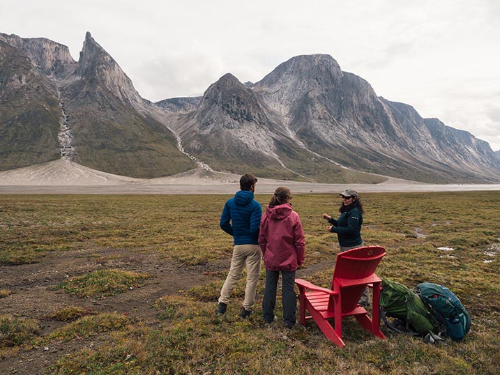 A Parks Canada guide talks with two visitors with Ulu Peak in the background.