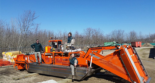 Three members of the Resource Conservation team pose for a picture on the park’s newly delivered Aquatic Weed Harvester. 