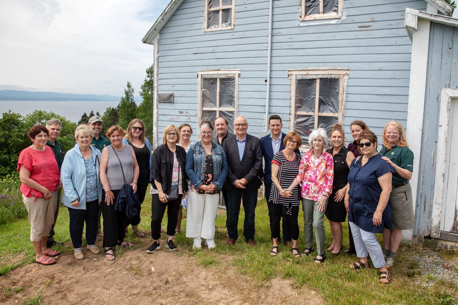 A group of approximately 15 persons poses next to a heritage house.