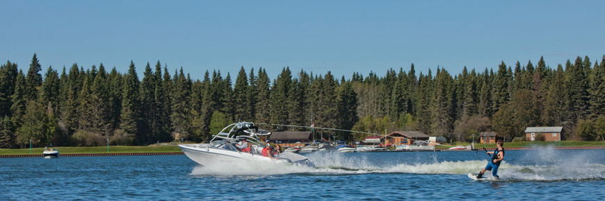 A motorboat pulls a wake boarder through the lake. 