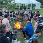 Dozens of people gathered around a campfire.