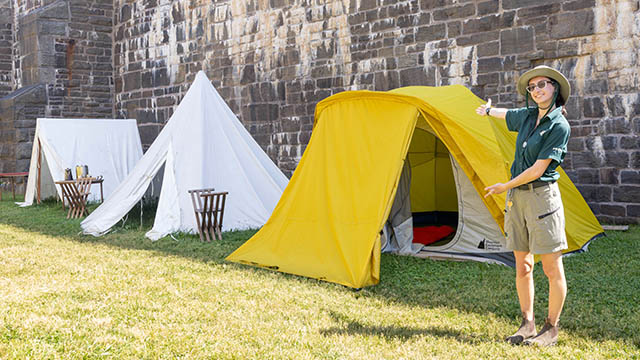 Parks Canada staff next to two historic tents and one modern tent.