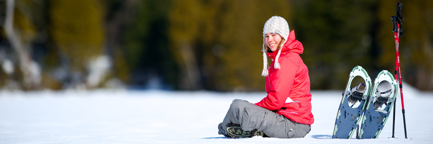 A woman sitting in the snow at La Maurice National Park with her snowshoes beside her.