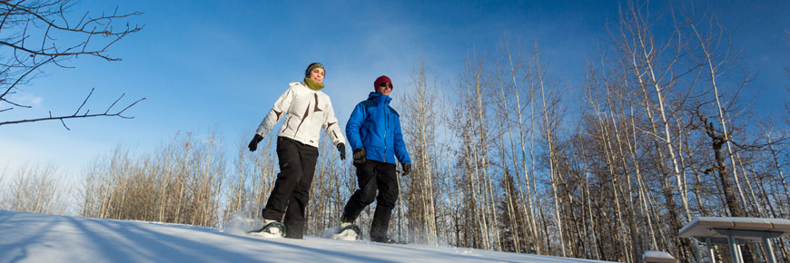 Two adults in action snowshoeing at Elk Island National Park.