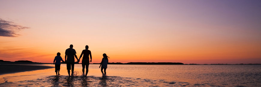 Visitors walk into the water on Shallow Bay Beach