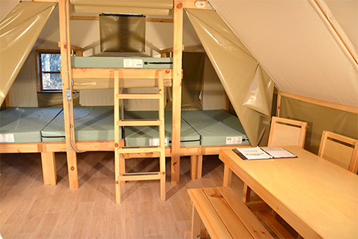 Interior of oTENTik showing bunkbeds that sleep 6, and a table and chairs.