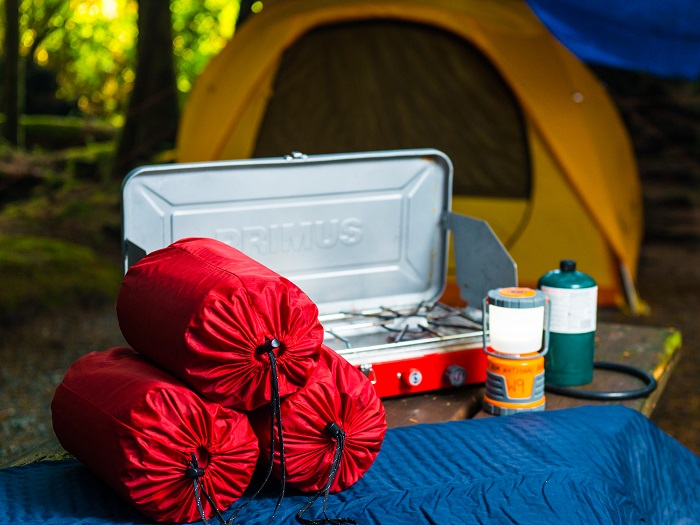Camping equipment is displayed in front of a yellow tent