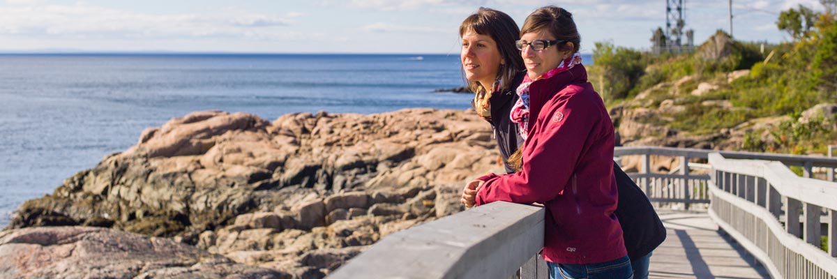 Two visitors whale watching from the shore at Saguenay–St. Lawrence Marine Park.