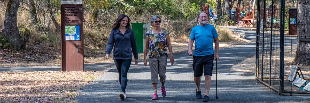 Three adults walk along an accessible path at Fort Rodd Hill and Fisgard Lighthouse National Historic Sites.