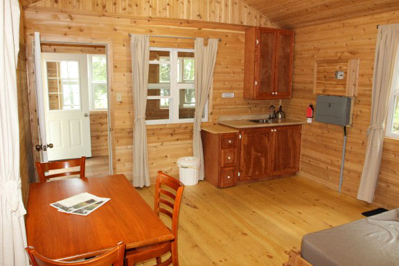 The kitchen area inside a cabin: a table, chairs, a counter with a sink and a kitchen cabinet.