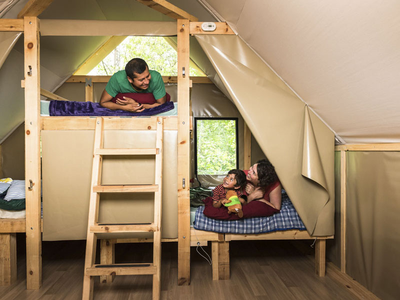 A family enjoying their stay in an oTENTik. People are lying down on the beds.