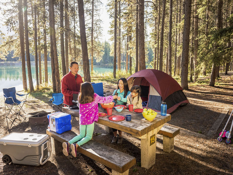 A family enjoys breakfast at their campsite near the water on a sunny fall morning at Two Jack Lakeside Campground. 