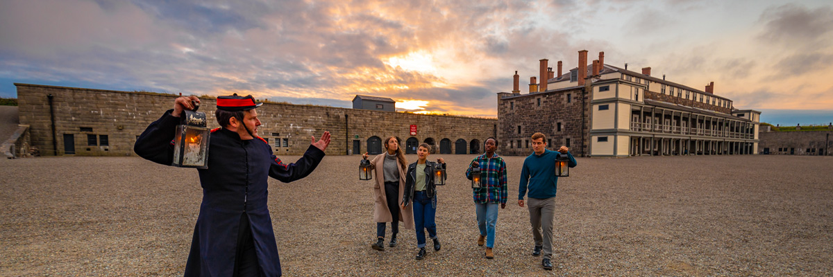 Visitors on a guided tour inside a stone building holding lanterns. 