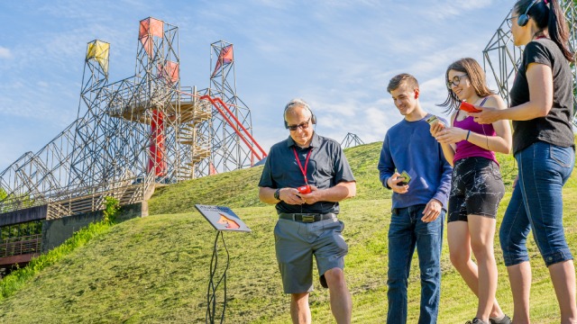 Four visitors with electronic devices following the audio tour.