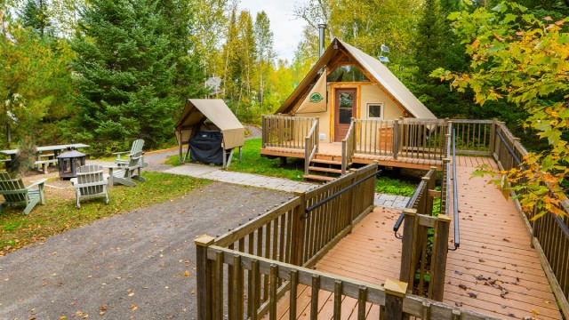 An oTENTik in autumn with an access ramp, BBQ and outdoor fireplace.